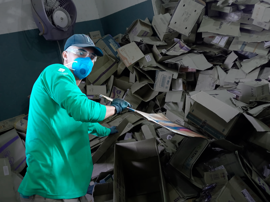 Catador trabalha em uma pilha de papelão