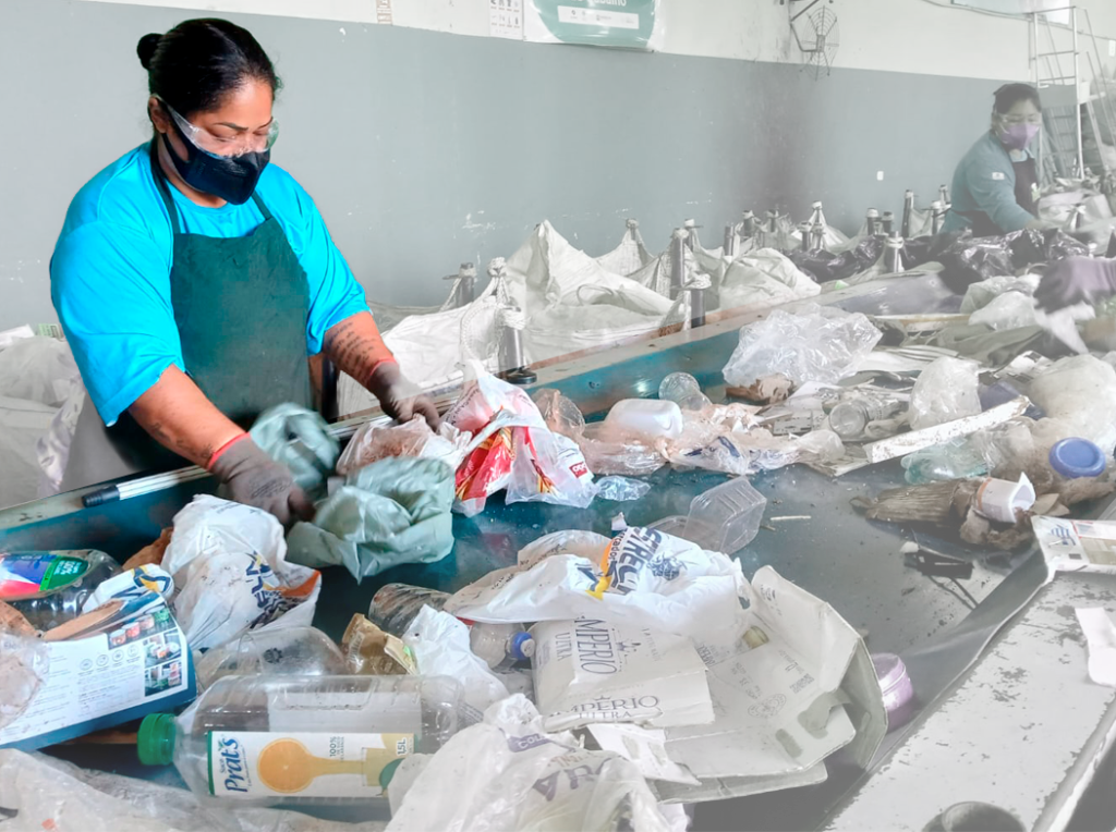 Catadora separa lixo em uma esteira.